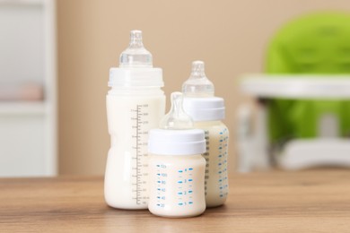 Photo of Feeding bottles with milk on wooden table indoors