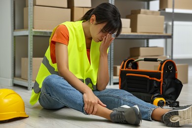 Accident at work. Injured woman with toolkit on floor in warehouse