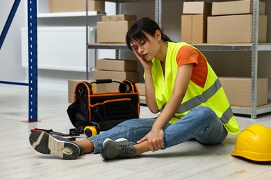 Photo of Accident at work. Injured woman with toolkit on floor in warehouse