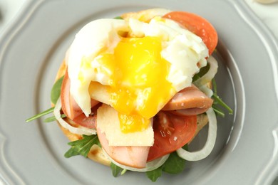 Photo of Tasty brunch. Poached egg, ham, tomato, arugula and bun on table, above view