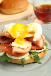 Photo of Tasty brunch. Poached egg, ham, tomato, arugula and bun on table, closeup