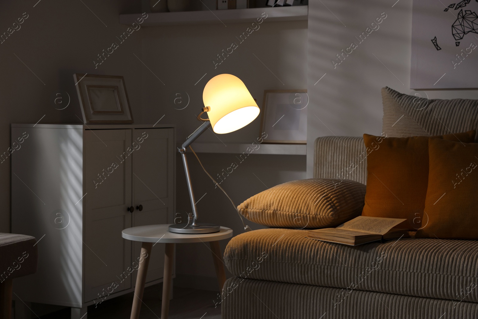 Photo of Stylish night lamp on side table near sofa in room. Interior design