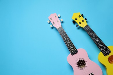 Photo of Two ukuleles on light blue background, top view. Space for text