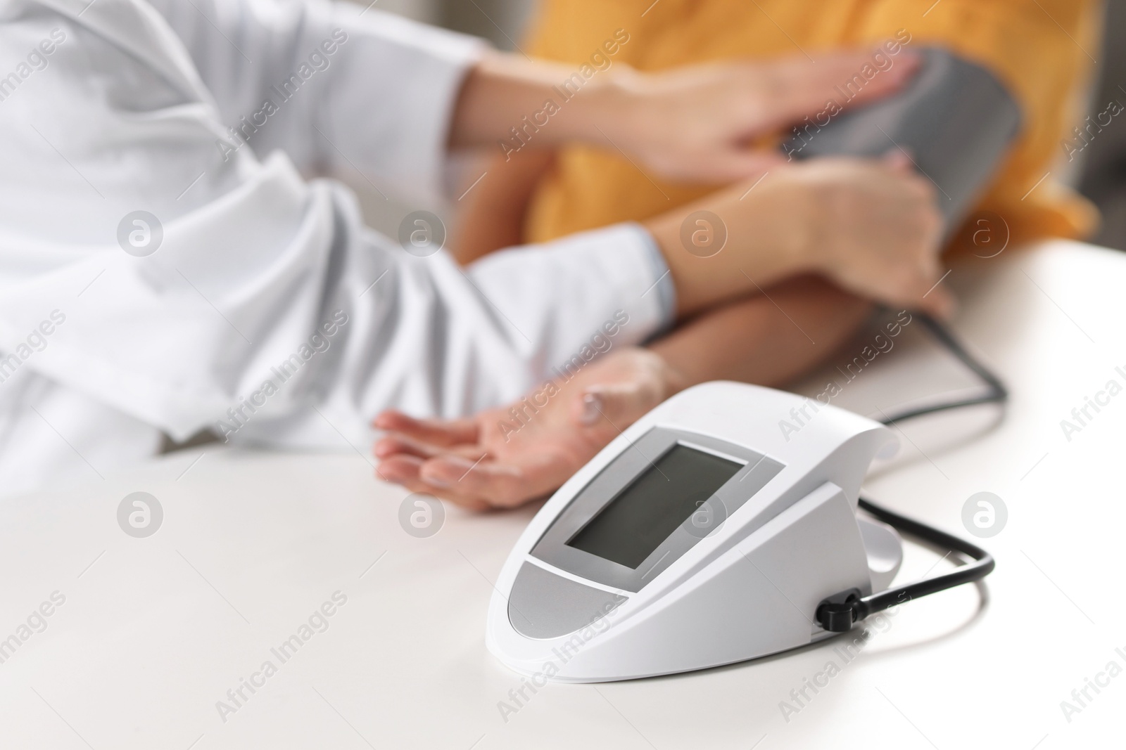 Photo of Doctor measuring senior woman's blood pressure during appointment in hospital, closeup