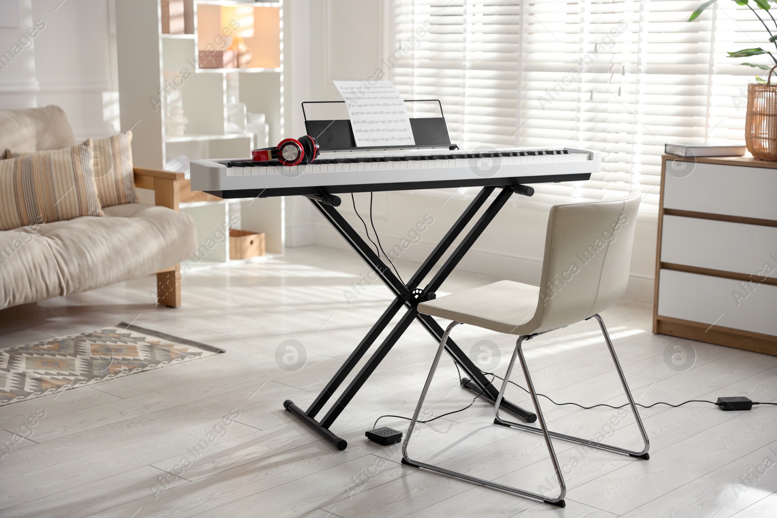 Photo of Synthesizer with music sheet, headphones and chair indoors