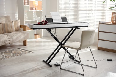 Photo of Synthesizer with music sheet, headphones and chair indoors