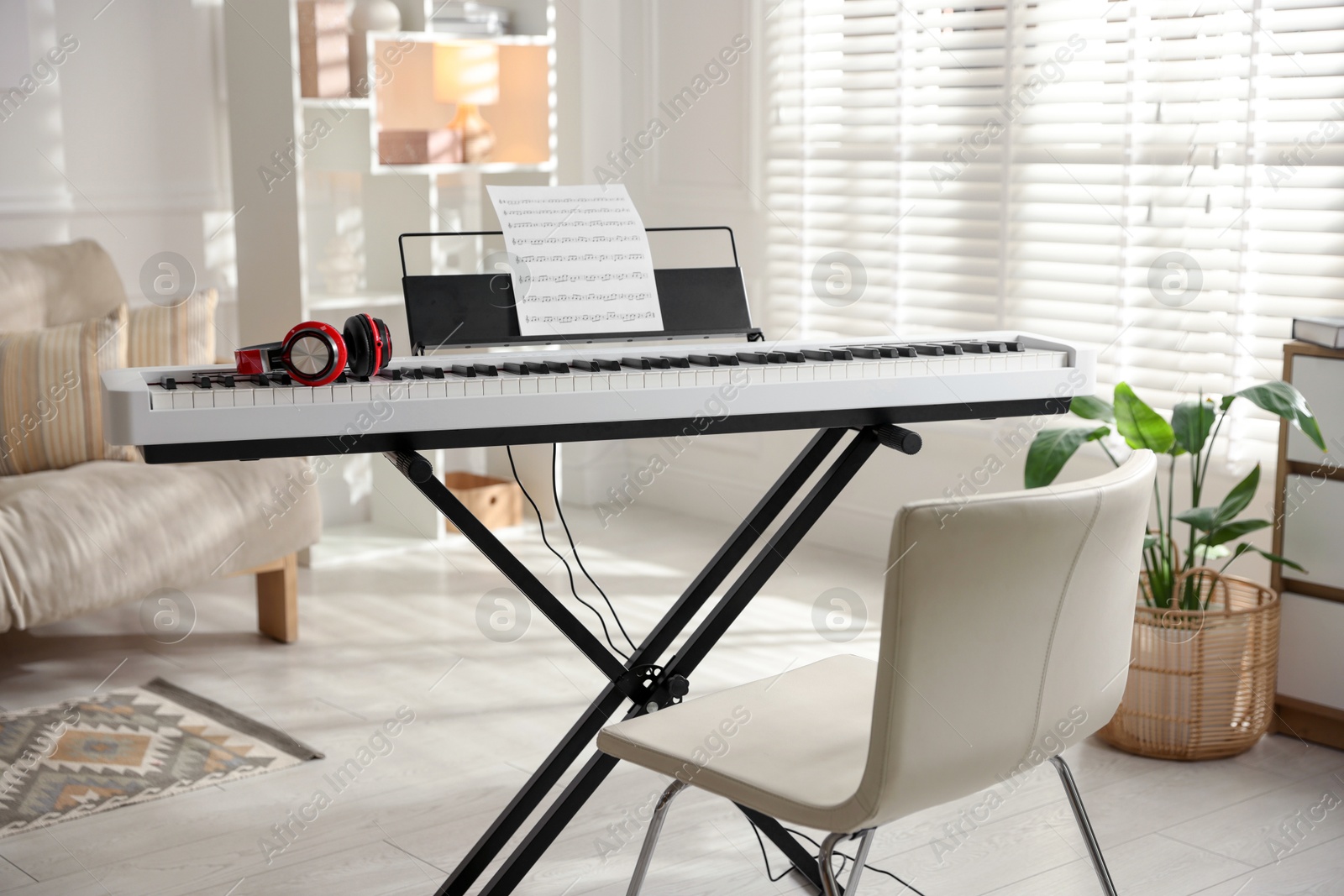 Photo of Synthesizer with music sheet, headphones and chair indoors