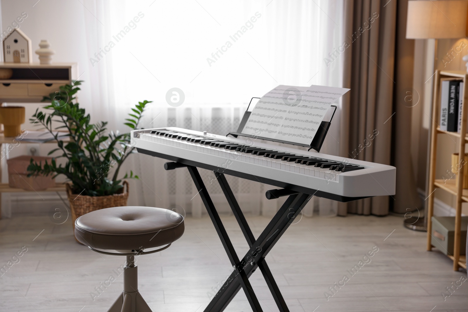 Photo of Synthesizer with music sheets and stool indoors