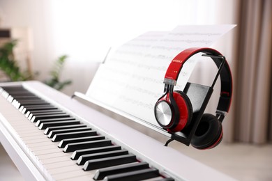 Photo of Synthesizer with music sheets and headphones indoors, closeup