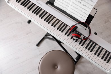 Photo of Synthesizer with music sheets, headphones and stool indoors, top view