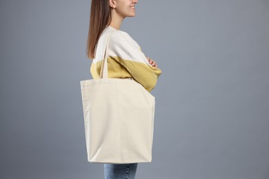 Photo of Woman with blank shopper bag on grey background, closeup. Mockup for design