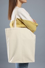 Photo of Woman with blank shopper bag on grey background, closeup. Mockup for design