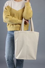 Photo of Woman with blank shopper bag on grey background, closeup. Mockup for design