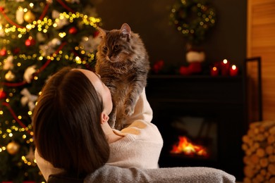 Photo of Woman with cute cat in room decorated for Christmas, space for text