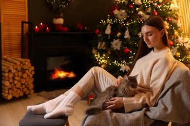 Photo of Woman with cute cat in room decorated for Christmas