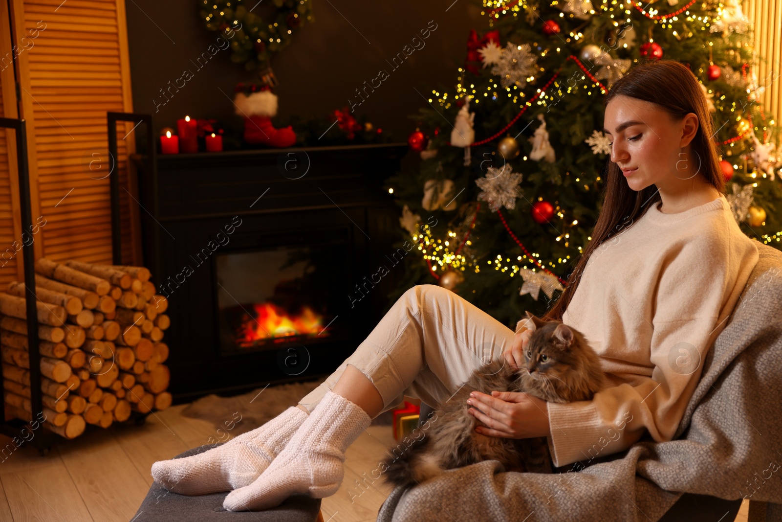 Photo of Woman with cute cat in room decorated for Christmas