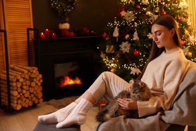 Photo of Woman with cute cat in room decorated for Christmas