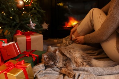 Photo of Woman and cute fluffy cat in room decorated for Christmas, closeup