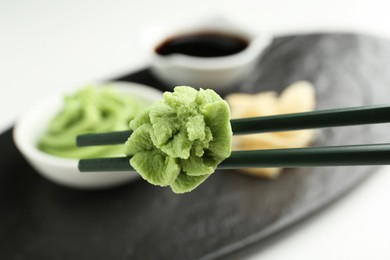 Photo of Chopsticks with hot wasabi paste on blurred background, closeup