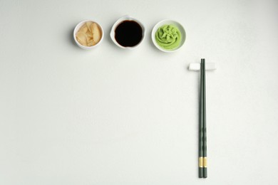 Photo of Hot wasabi paste, soy sauce, ginger and chopsticks on light textured table, flat lay. Space for text