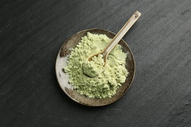 Photo of Plate with dry wasabi powder and spoon on dark textured table, top view