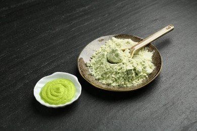 Photo of Plate with dry wasabi powder, spoon and paste on dark textured table, closeup