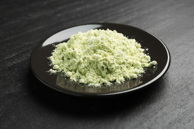 Photo of Plate with dry wasabi powder on dark textured table, closeup