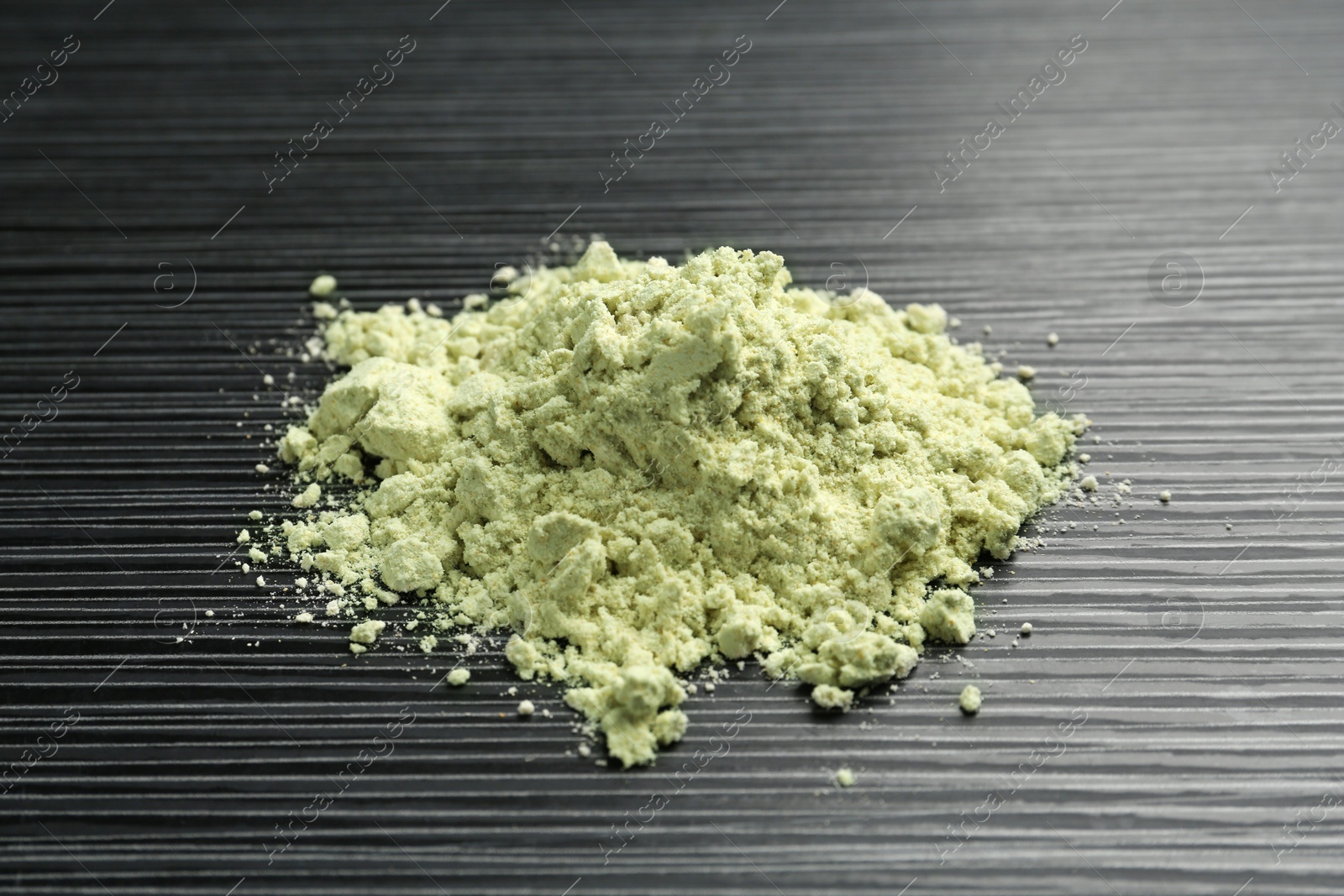 Photo of Pile of wasabi powder on black textured table, closeup