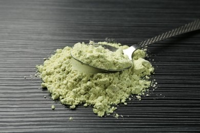 Photo of Pile of wasabi powder and spoon on black textured table, closeup