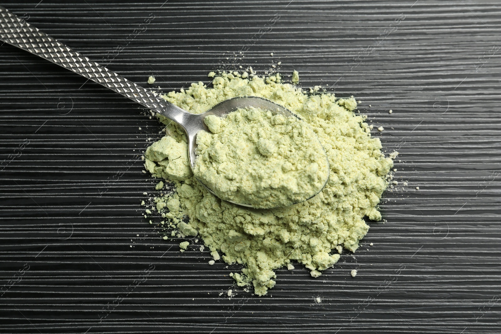 Photo of Pile of wasabi powder and spoon on black textured table, top view