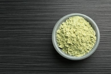 Photo of Wasabi powder in bowl on black textured table, top view. Space for text