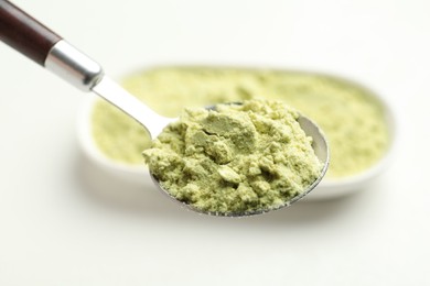 Photo of Spoon with dry wasabi powder on blurred background, closeup