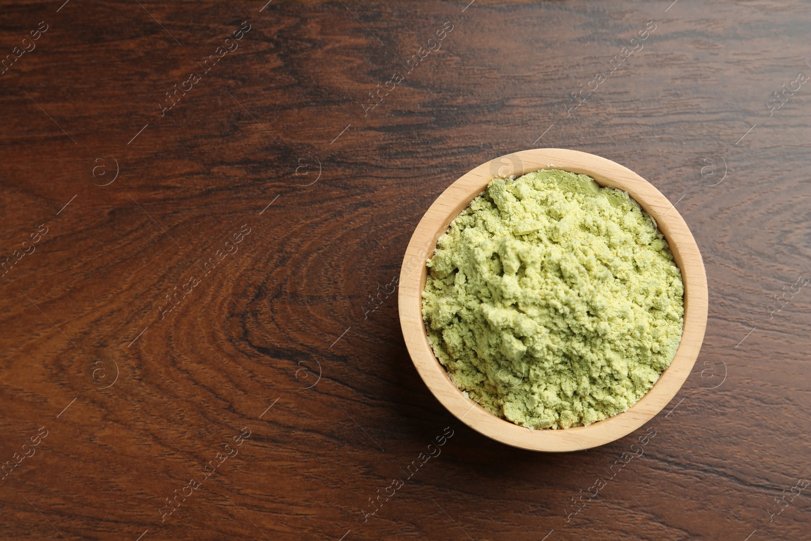 Photo of Dry wasabi powder in bowl on wooden table, top view. Space for text