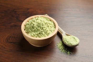 Photo of Dry wasabi powder in bowl and spoon on wooden table, closeup