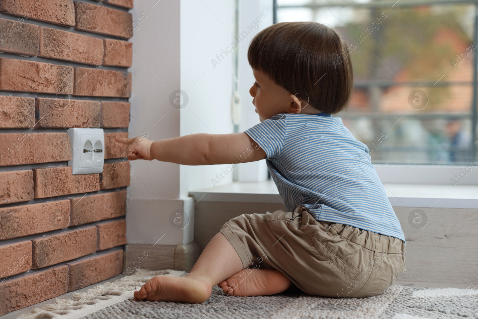 Photo of Little boy playing with electrical socket at home. Child in danger