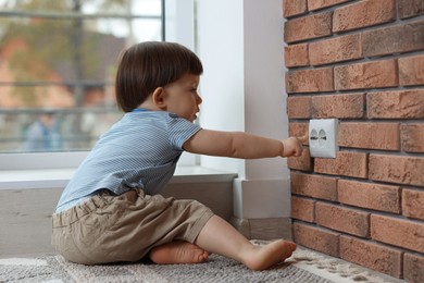 Photo of Little boy playing with electrical socket at home. Child in danger