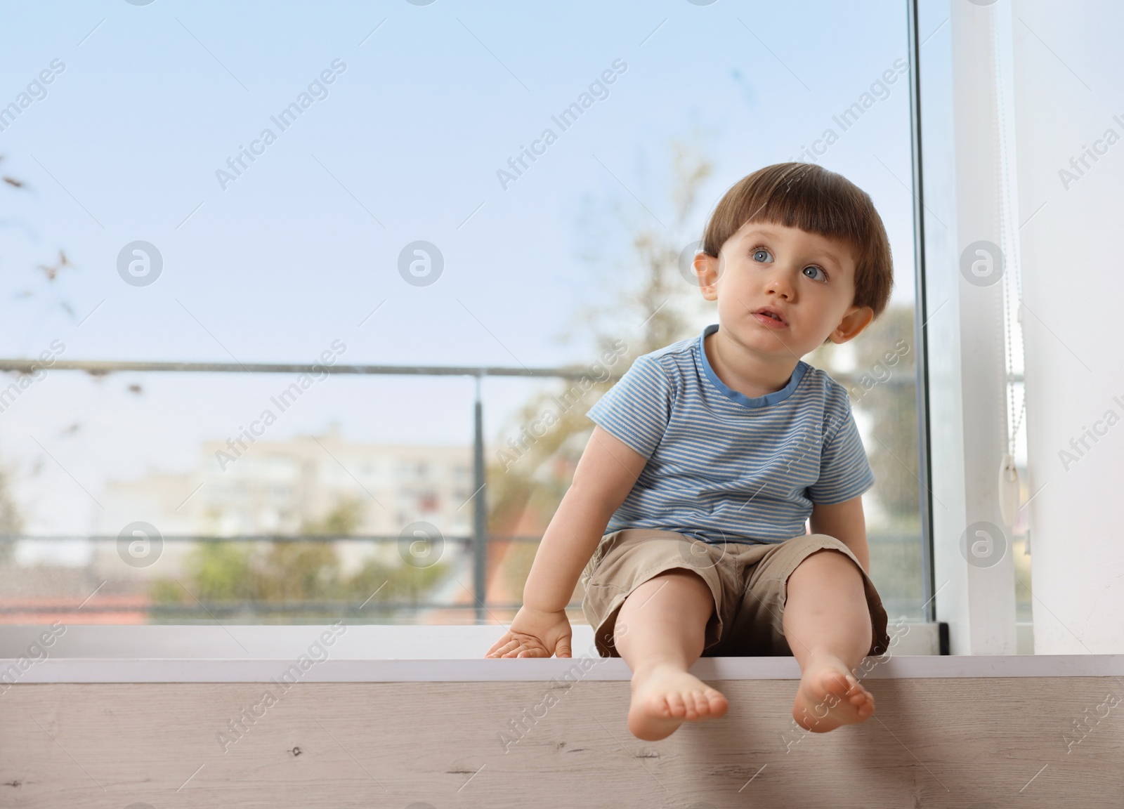 Photo of Little boy sitting on window sill, space for text. Child in danger