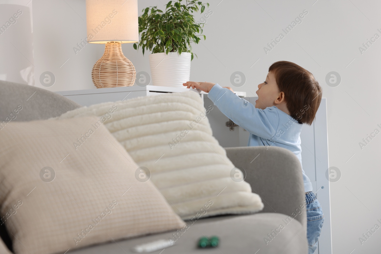 Photo of Little boy finding cabinet with pills at home. Child in danger