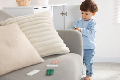 Photo of Little boy with pills at home. Child in danger