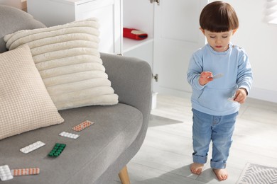 Photo of Little boy with pills at home. Child in danger