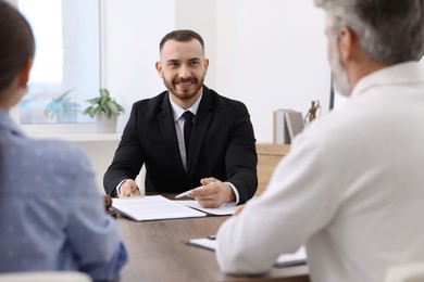 Photo of Man and woman having meeting with professional notary at wooden desk indoors