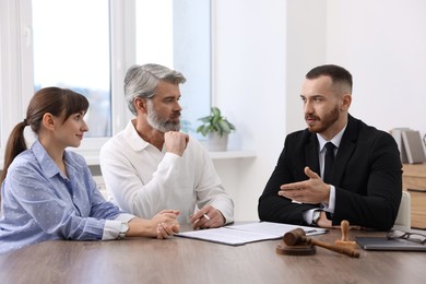 Couple having meeting with professional notary at wooden desk indoors