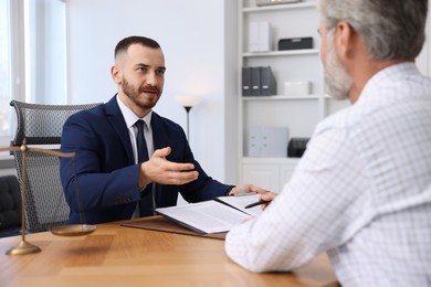 Man having meeting with professional notary at wooden desk indoors