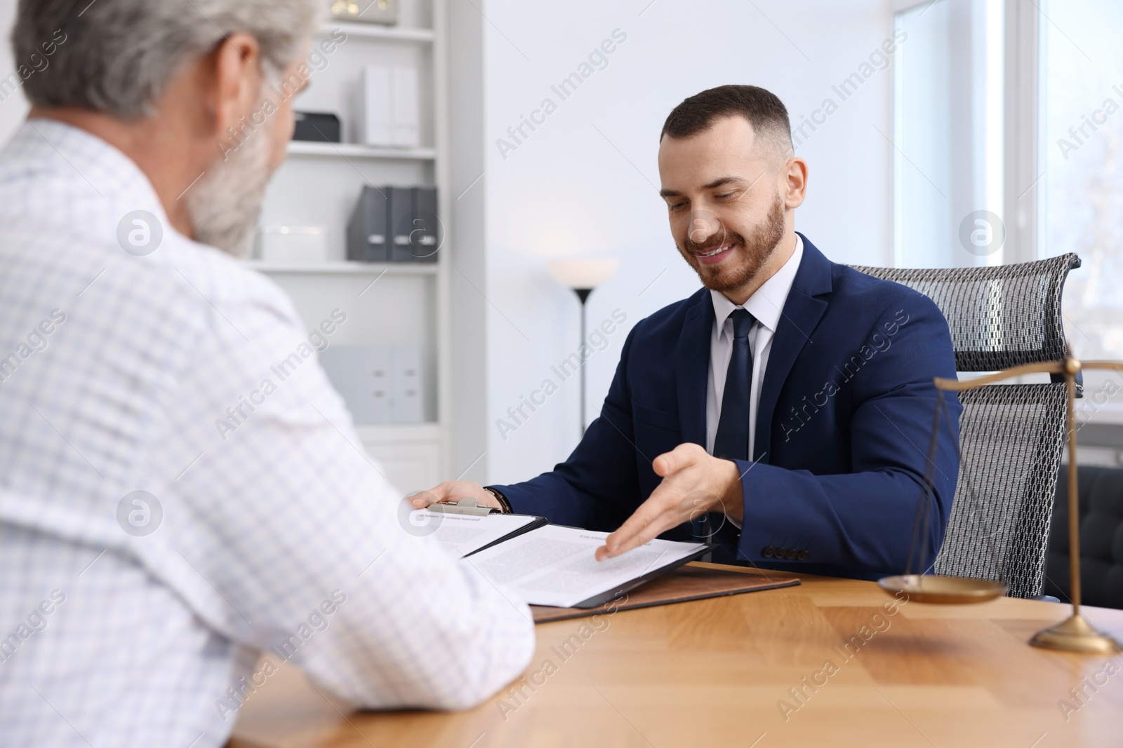 Photo of Man having meeting with professional notary at wooden desk indoors