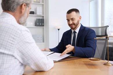 Man having meeting with professional notary at wooden desk indoors