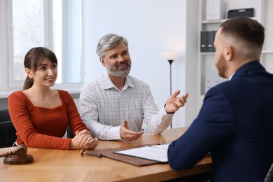 Couple having meeting with professional notary at wooden desk indoors