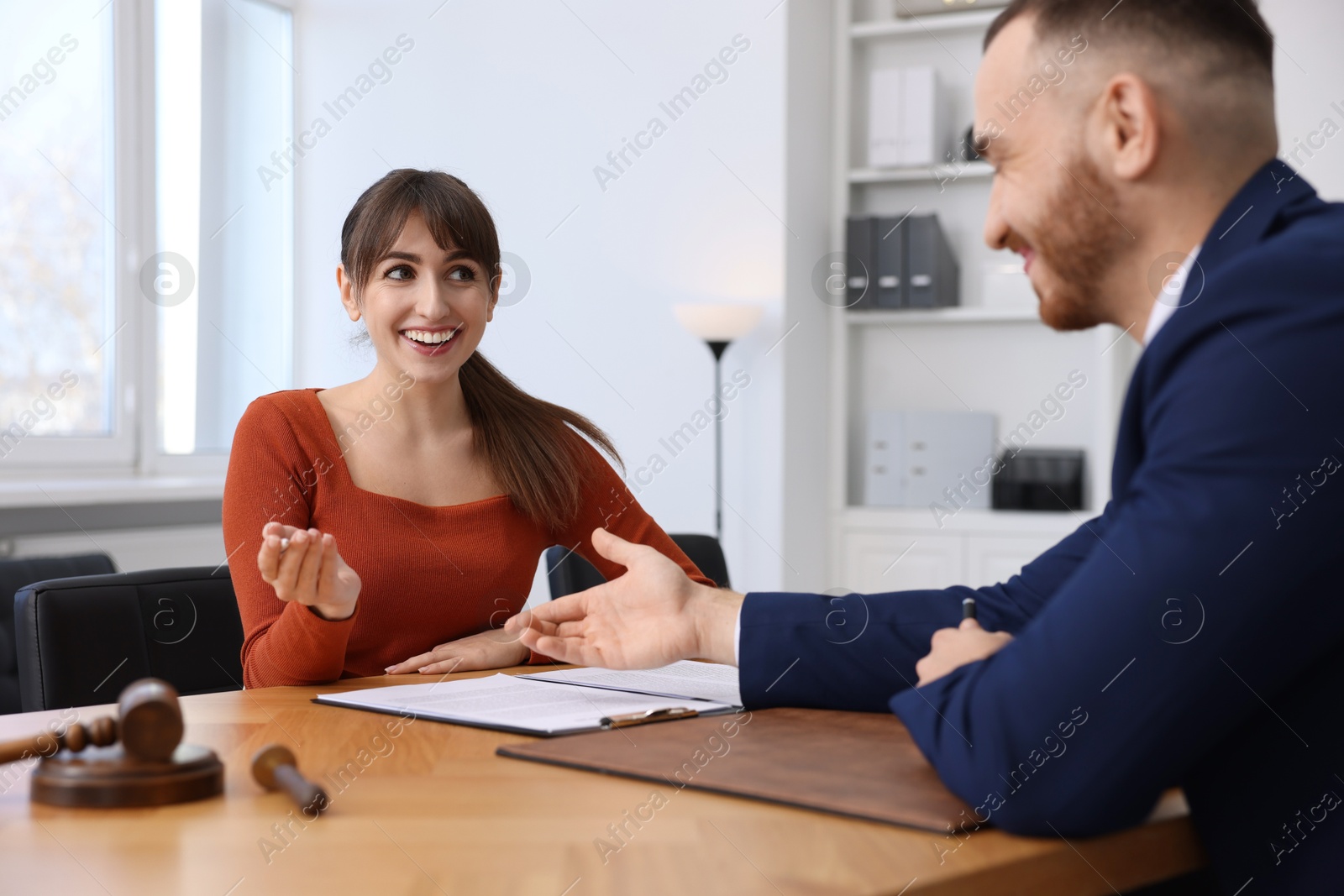 Photo of Woman having meeting with professional notary at wooden desk indoors