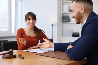 Photo of Woman having meeting with professional notary at wooden desk indoors