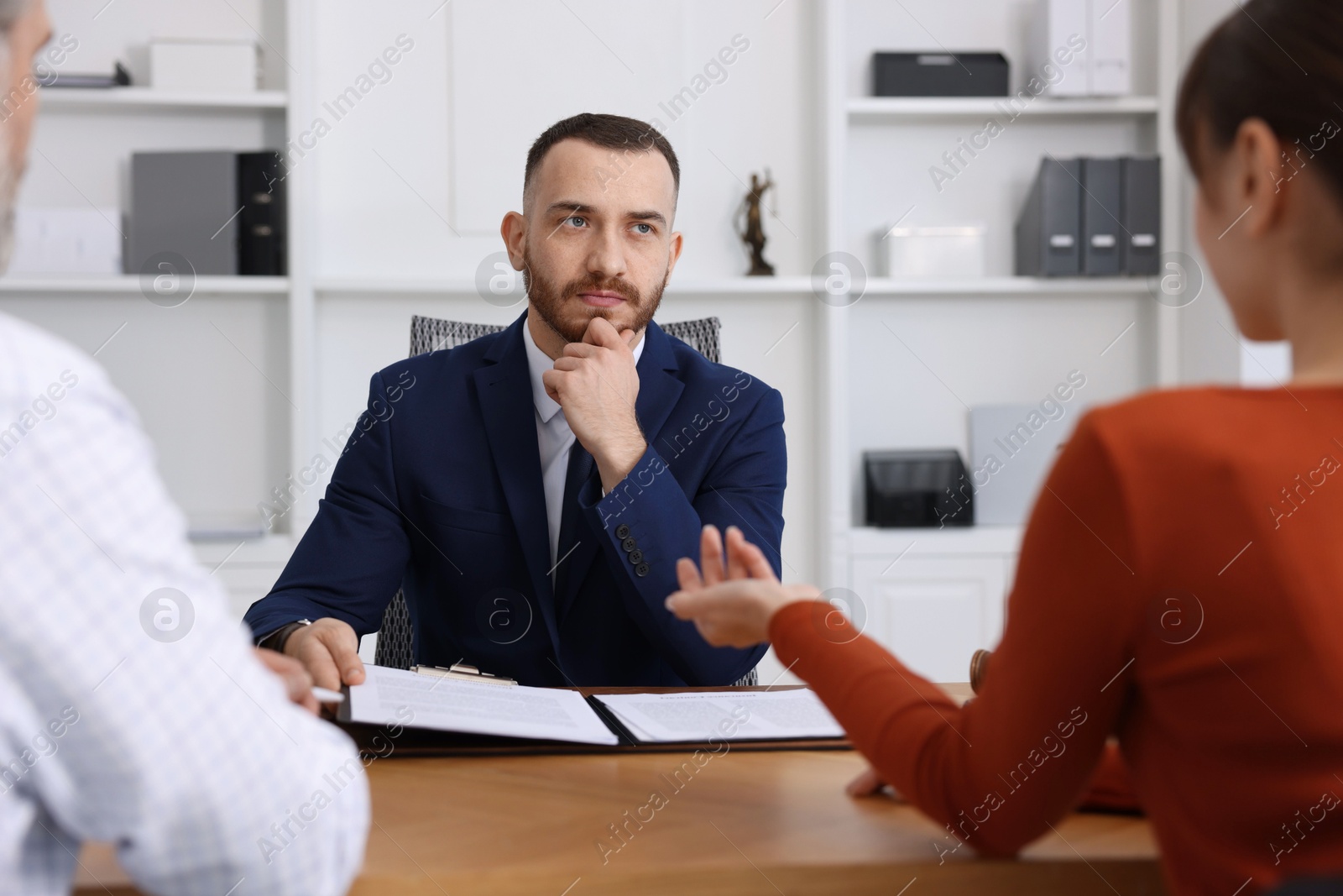 Photo of Man and woman having meeting with professional notary at wooden desk indoors