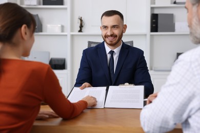 Photo of Clients signing notarial paperwork during meeting with lawyer at wooden desk indoors